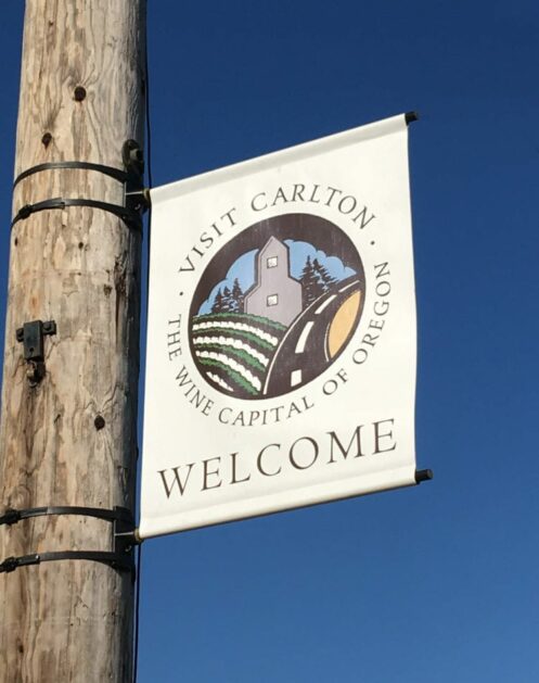 A sign on a pole reads Visit Carlton, the Wine Capital of Oregon, Welcome